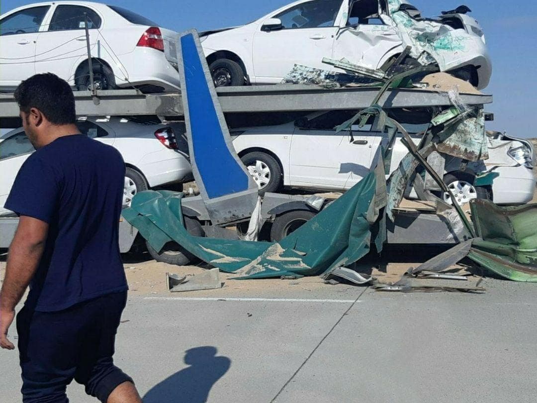 Car-carrying trailer collides with a truck, several cars damaged